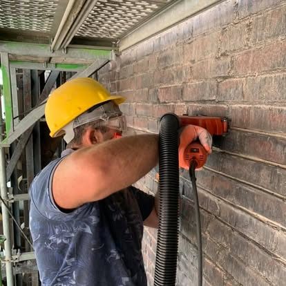 Handwerker mit gelbem Helm entfernt alte Fugen 