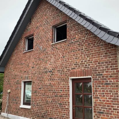 Zwei Fenster und eine Tür an einer roten Backsteinfassade eines Hauses welches neu verfugt wurde 