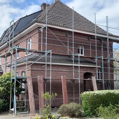 Renoviertes Haus mit Gerüst und Grünpflanzen im Vordergrund.