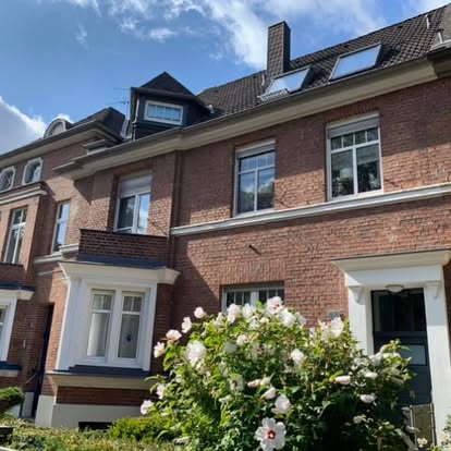 Zweifamilienhaus mit roter Backsteinfassade und blühenden Rosen im Vordergrund welches neu verfugt wurde