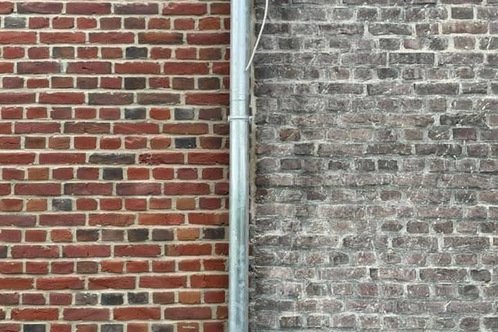 Rote Ziegelmauer auf der linken Seite, graue Klinkermauer auf der rechten Seite.