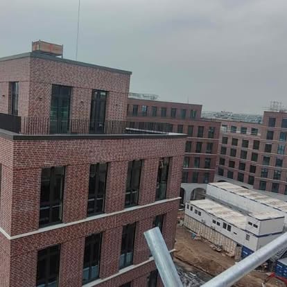 Blick auf moderne Backsteingebäude und Baustelle mit Baucontainern.